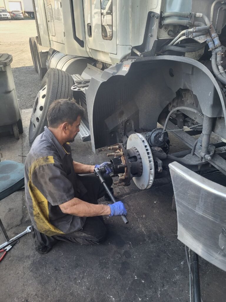 Mechanic tightening the front brake hub on a Mack truck