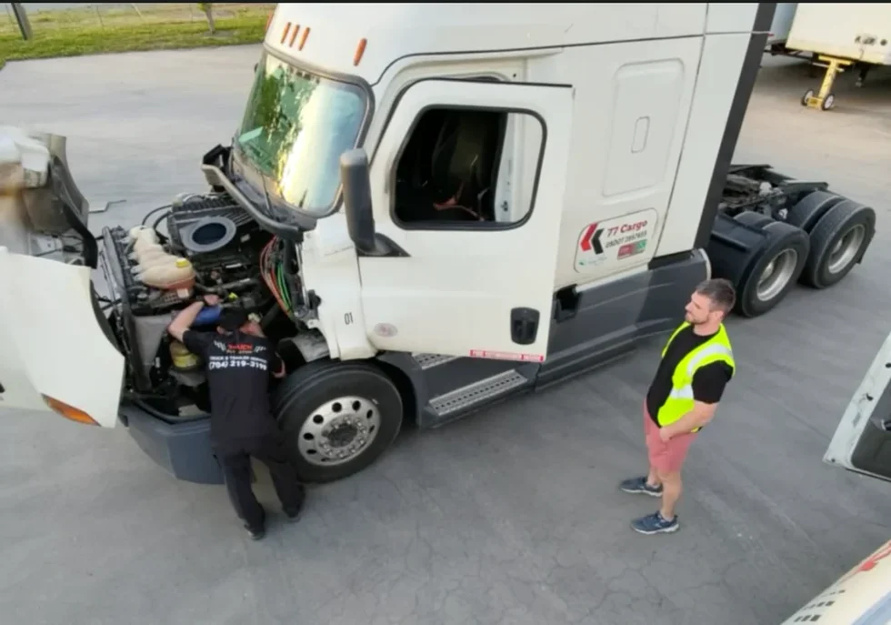 Truck Pit Stop employees working under the hood of a white semi-truck