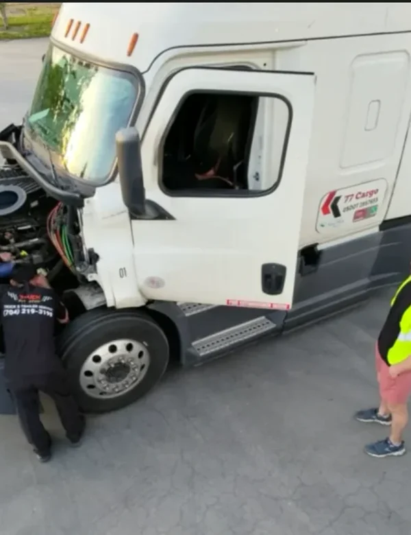 Truck Pit Stop employees working under the hood of a white semi-truck