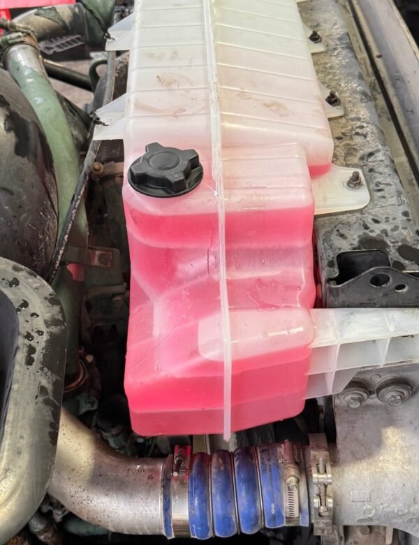 Pink coolant in a semi truck surge tank during a winter check at Truck Pit Stop in Matthews, North Carolina