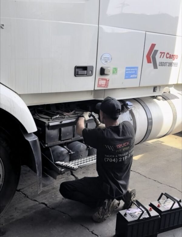 Truck Pit Stop mechanic replacing the batteries on a Volvo semi truck before winter in Matthews, North Carolina